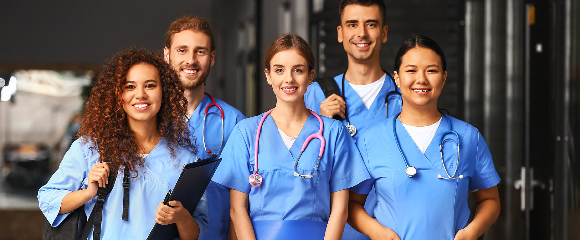 group of medical personnel holding their bags or wearing a stethoscope smiling at the camera