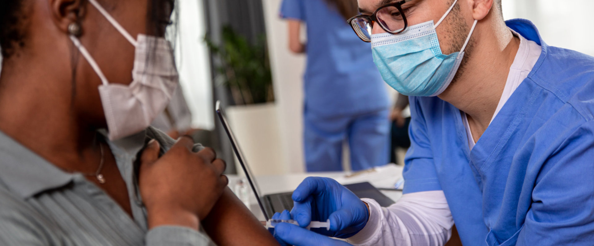 Male nurse with mask giving vaccine to patient in clinic